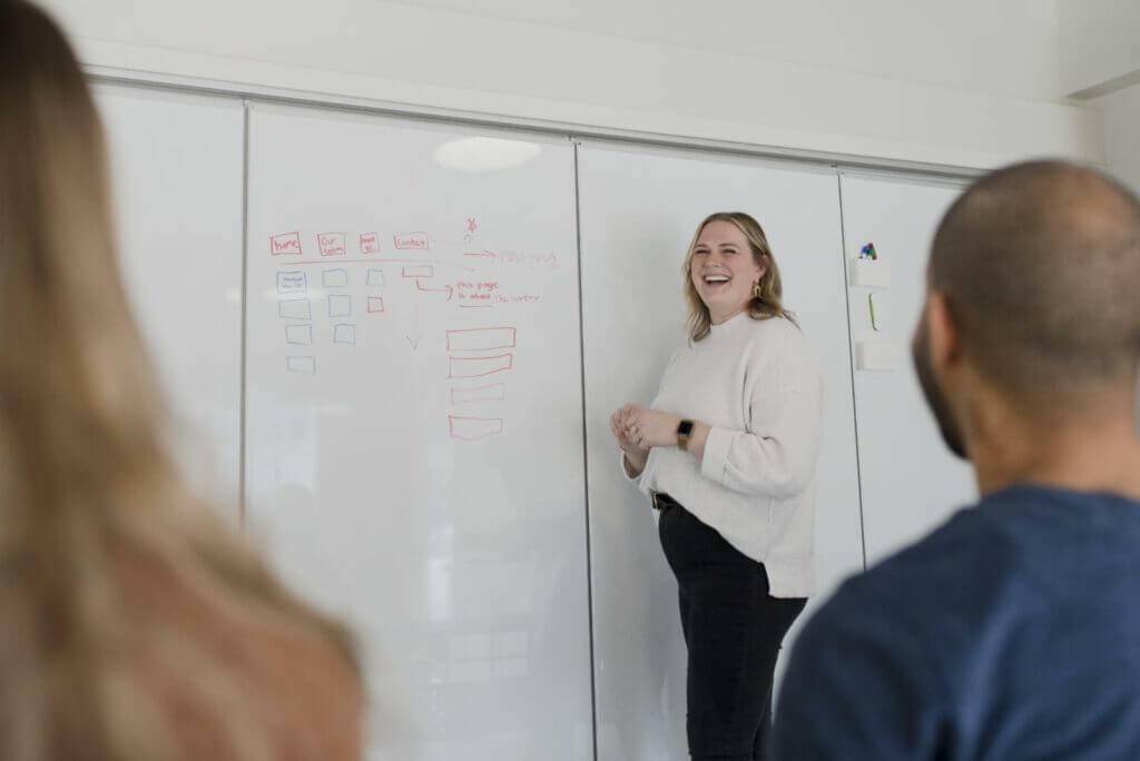 Lindsey LaMair, VP of Strategy, standing at a whiteboard talking to a room of employees